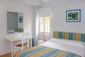 a bedroom with a bed and a desk and a chair at Hostal Alba in La Mata