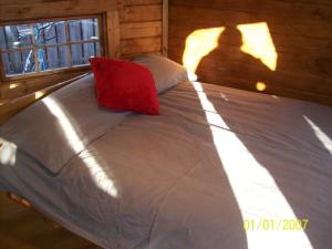 a bed with a red pillow in a wooden cabin at The Hobbit House in Fort William +3 photos
