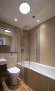 a bathroom with a toilet and a tub and a sink at Wakeford Cottage in Worthing