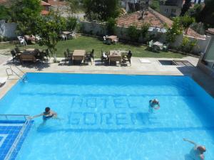 two people swimming in a pool with a sign in the water at Hotel Goreme Sakura in Pamukkale