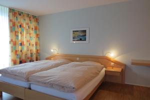 a bedroom with a bed with two lights on at Hotel Restaurant Sternen in Guggisberg