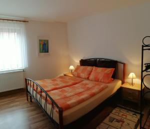 a bedroom with a bed with orange sheets and a window at Atelier Reinhart in Rauhenebrach