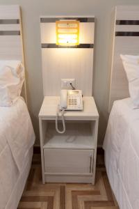 a phone is sitting on a nightstand between two beds at Mercé Hotel in Tacna