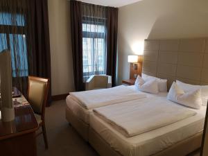 una camera d'albergo con un grande letto e una scrivania di Hotel Am Blauen Wunder a Dresda