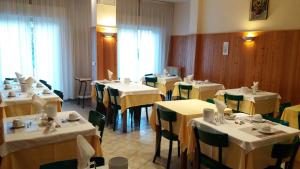 a restaurant with white tables and green chairs at Albergo Moretti in Senigallia