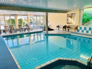 a large swimming pool with blue tiles in a building at Hotel Restaurant Le Clos in Besse-et-Saint-Anastaise