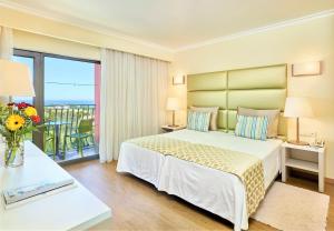 a bedroom with a large bed and a balcony at Hotel Baia Grande in Albufeira