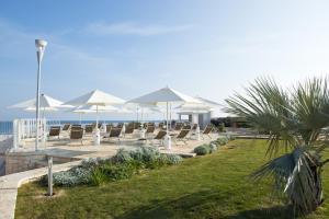 - une rangée de chaises et de parasols sur la plage dans l'établissement Vilu Suite Mare, à Polignano a Mare