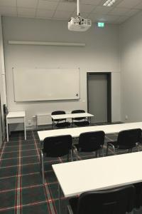 ein Klassenzimmer mit weißen Tischen und Stühlen sowie einem Whiteboard in der Unterkunft Rasta Värnamo in Värnamo