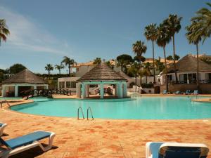 una grande piscina con sedie e gazebo di Luxury 2 Bedroom Apartment with Private Garden a Almancil
