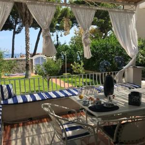 un patio con mesa y sillas y vistas al océano en VILLA DEL MELOGRANO, en Patti