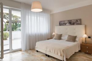 ein weißes Schlafzimmer mit einem Bett und einem großen Fenster in der Unterkunft Dante 124 | Appartamenti a Riccione in Riccione