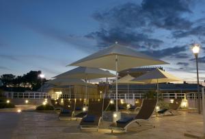 - un groupe de chaises et de parasols la nuit dans l'établissement Vilu Suite Mare, à Polignano a Mare