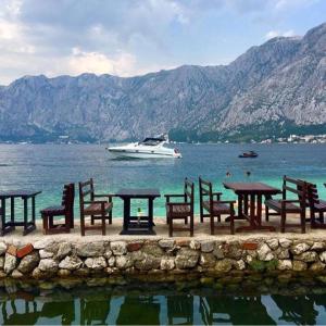 a group of tables and chairs and a boat in the water at Apartments Vila Marija in Kotor