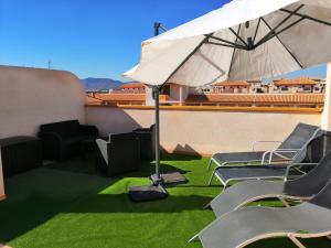 マール・デ・クリスタルにあるRibera Beach 1 Apartment Elisaのパティオ(芝生の椅子、屋根の上にパラソル付)