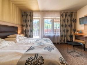 um quarto de hotel com uma cama, uma secretária e uma janela em Hotel Zakopane Wellness & SPA ex Korona Tatr em Zakopane