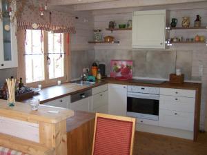 cocina con armarios blancos y mesa de madera en Pension Frauenschuh, en Hirschbach
