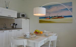 a white kitchen with a table with a bowl of fruit at Vilu Suite Mare in Polignano a Mare