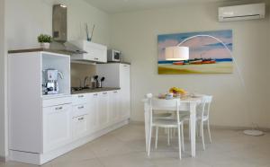 a kitchen with white cabinets and a table with chairs at Vilu Suite Mare in Polignano a Mare
