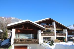 um edifício com uma varanda com neve no chão em Alpen - Apartments em Garmisch-Partenkirchen