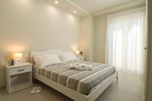 a white bedroom with a bed with two towels on it at Vilu Suite Mare in Polignano a Mare