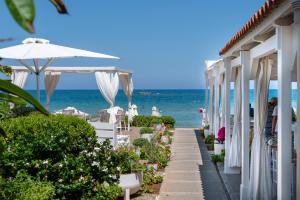 a pathway to a beach with white buildings and the ocean at Talgo Suites in Stalida