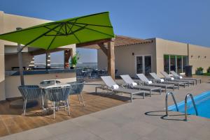 a group of chairs and an umbrella next to a pool at Galeria Plaza Irapuato in Irapuato