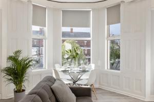 a living room with a table and chairs and windows at Cyprus View Apartment 2 in Belfast