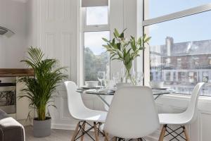 a dining room with a table and white chairs and a window at Cyprus View Apartment 2 in Belfast