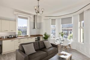 a living room with a brown couch and a kitchen at Cyprus View Apartment 2 in Belfast