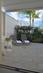 a patio with two chairs and a table and palm trees at Vilu Suite Mare in Polignano a Mare