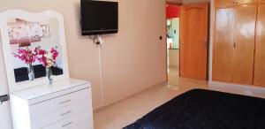 a room with a white dresser with a tv on the wall at Appartement de luxe centre ville les "Dunes d'Or" in Oujda