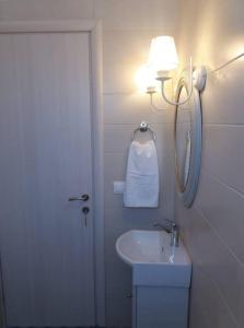 a bathroom with a sink and a light next to a door at Kedraki in Kalamaki