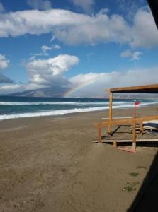 a picnic table on a beach with a rainbow in the background at Kedraki in Kalamaki