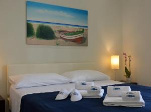 a bedroom with two beds with towels and a painting at Vilu Suite Mare in Polignano a Mare