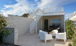 a patio with white chairs and a table at Vilu Suite Mare in Polignano a Mare