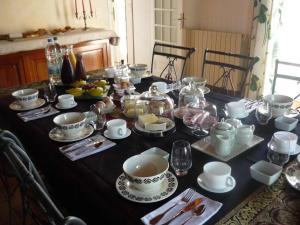 una mesa negra con tazas y platos de comida. en Au Mas du Soleil, en Senouillac