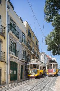 Dos trolebuses están estacionados en una calle de la ciudad. en São Vicente 1797 Apartments en Lisboa