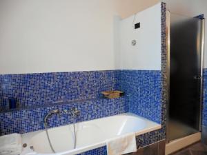 y baño de azulejos azules con bañera. en Appartamento il Veggio, en Poggio a Caiano