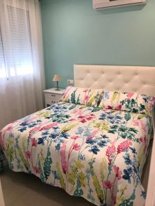 um quarto com uma cama com colcha floral em APARTAMENTO AVENIDA 2 em Nerja