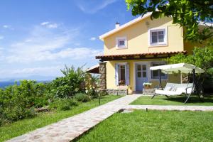 a yellow house with a patio and an umbrella at Aelia & Melitta Villas in Perdhika