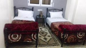 um quarto com 2 camas e uma mesa com mesa de cabeceira em Gite porte oasis em Er Rachidia