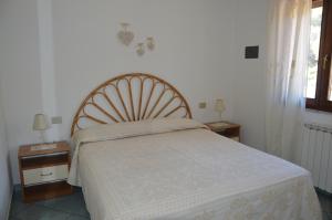 a bed in a bedroom with two tables and a window at Appartamento Li Puntiti 3 in Budoni