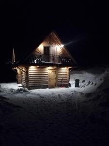 a wooden cabin in the snow at night at Domek "Pod Lubaniem" in Grywałd +7 photos