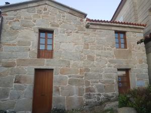 een stenen huis met twee deuren en twee ramen bij Casa Mariñeira in Combarro