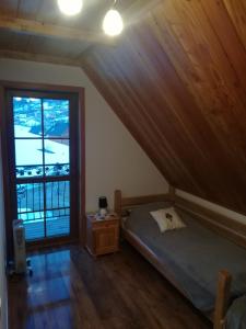 ein Schlafzimmer mit einem Bett und einem großen Fenster in der Unterkunft Domek "Pod Lubaniem" in Grywałd
