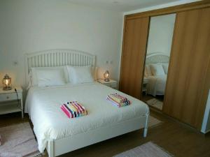 a bedroom with a white bed with pillows and a mirror at Ribalta Beach Houses in Ericeira