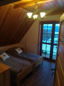 ein Schlafzimmer mit einem Bett in einem Zimmer mit einem Balkon in der Unterkunft Domek "Pod Lubaniem" in Grywałd