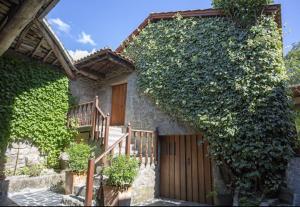- un bâtiment recouvert de lierre avec une porte en bois et des escaliers dans l'établissement Iberik Casa Vilamor, à Vilamor