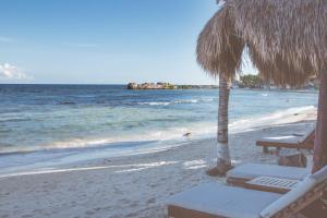 a beach with chairs and umbrellas on it at El Pez a Colibri Boutique Hotel in Tulum